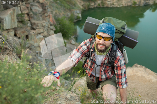 Image of Young caucasian man with backpack climbing the rock