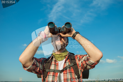 Image of Young caucasian man with backpack standing on the top of hill