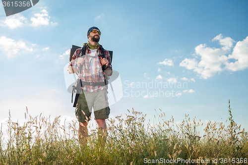 Image of Young caucasian man with backpack standing on the top of hill