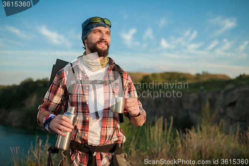 Image of Young caucasian man with backpack resting and drinking water