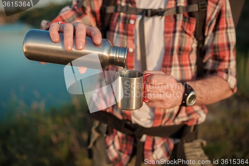 Image of Young caucasian man with backpack resting and drinking water