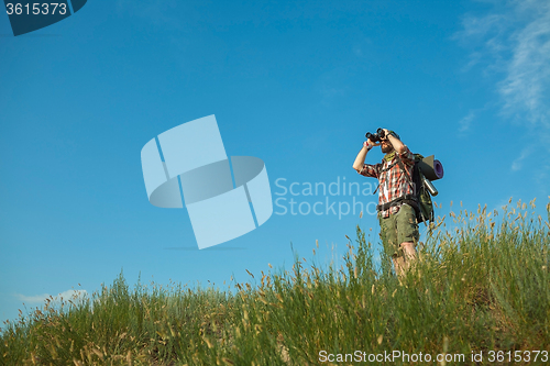 Image of Young caucasian man with backpack standing on the top of hill