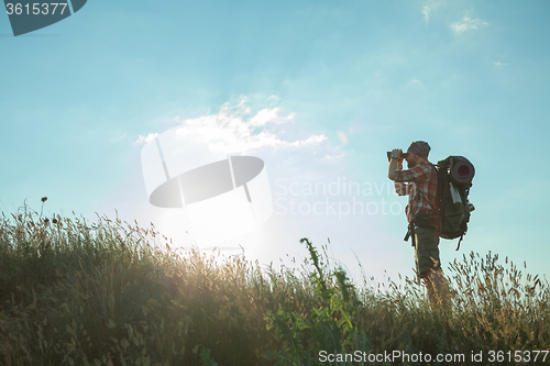 Image of Young caucasian man with backpack standing on the top of hill