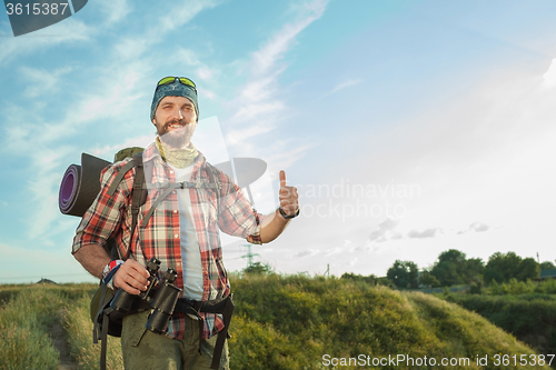 Image of Young caucasian man with backpack standing on the top of hill