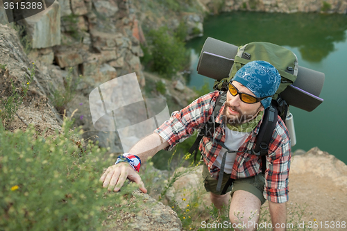 Image of Young caucasian man with backpack climbing the rock