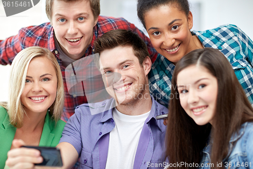 Image of group of happy students with smartphone at school