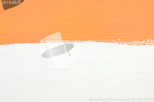 Image of Stripe of orange paint over white wooden background