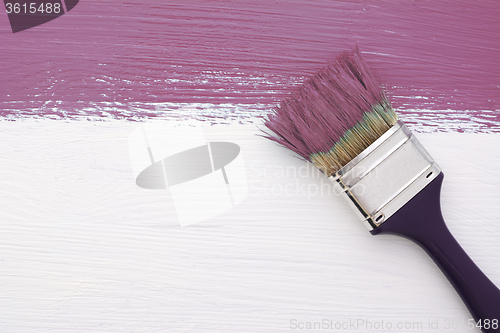 Image of Stripe of plum paint with a paintbrush on white