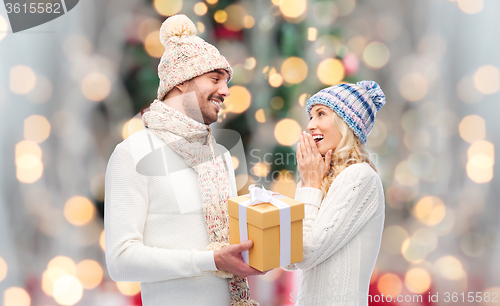 Image of smiling couple in winter clothes with gift box