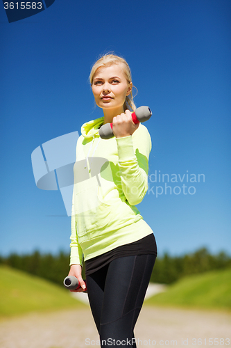 Image of sporty woman with light dumbbells outdoors