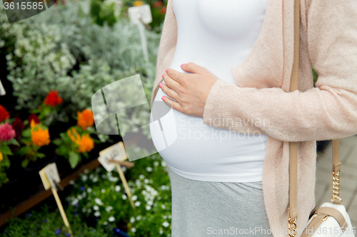 Image of pregnant woman choosing flowers at street market