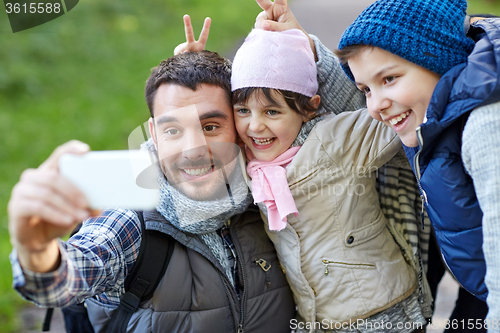 Image of family taking selfie with smartphone outdoors