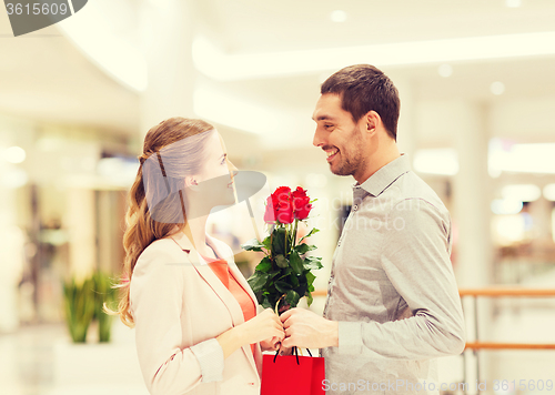 Image of happy young couple with flowers in mall