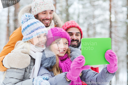 Image of smiling friends with tablet pc in winter forest