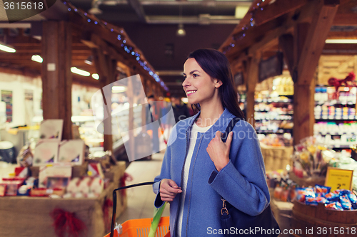 Image of happy young woman with food basket in market