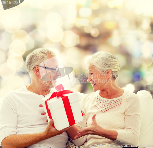 Image of happy senior couple with gift box at home