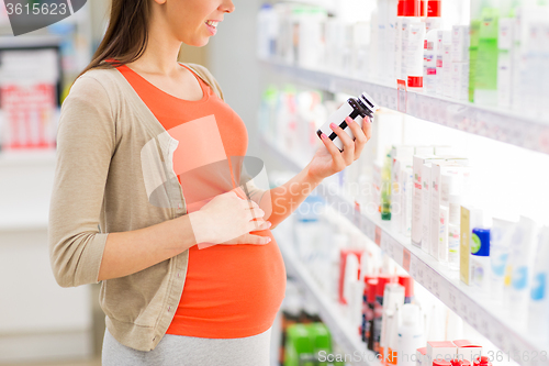 Image of happy pregnant woman with medication at pharmacy