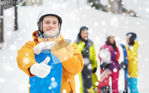 Image of happy young man with snowboard showing thumbs up