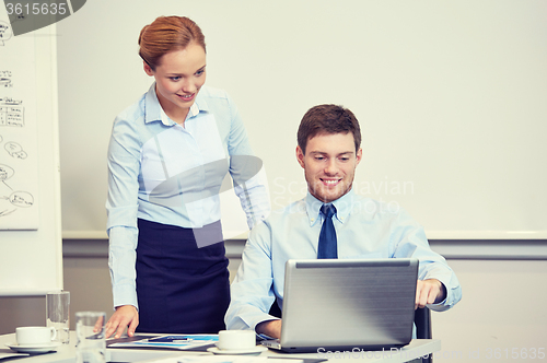 Image of smiling businesspeople with laptop in office