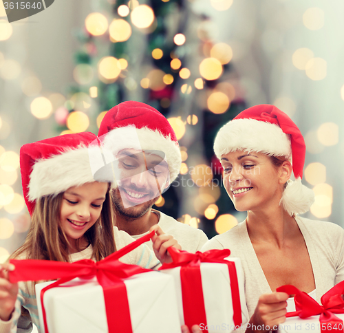 Image of happy family in santa helper hats with gift boxes