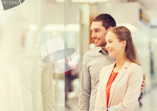 Image of happy couple looking to shop window in mall