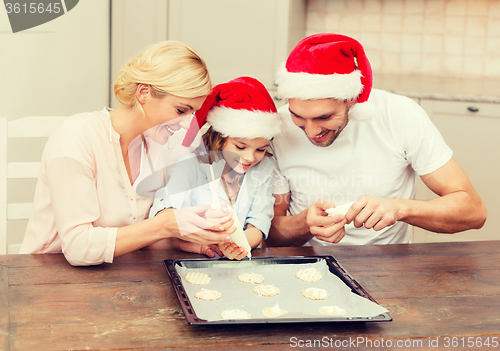 Image of happy family in santa helper hats making cookies