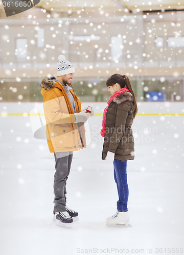 Image of happy couple with engagement ring on skating rink