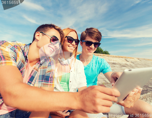 Image of group of smiling friends with tablet pc outdoors