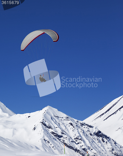 Image of Paraglider in sunny snowy mountains at nice day