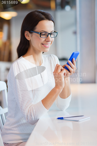Image of smiling woman with smartphone at cafe
