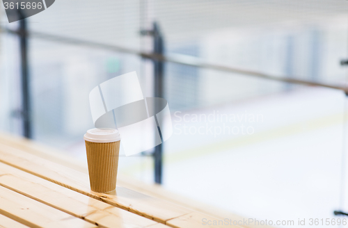 Image of close up of coffee cup on bench at skating rink