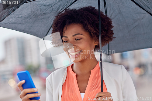 Image of businesswoman with umbrella texting on smartphone