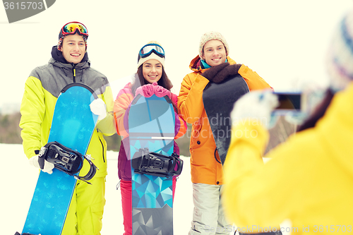 Image of happy friends with snowboards and smartphone