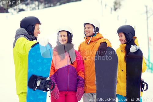 Image of happy friends in helmets with snowboards talking