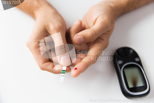 Image of close up of man checking blood sugar by glucometer