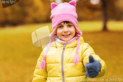 Image of happy little girl showing thumbs up outdoors