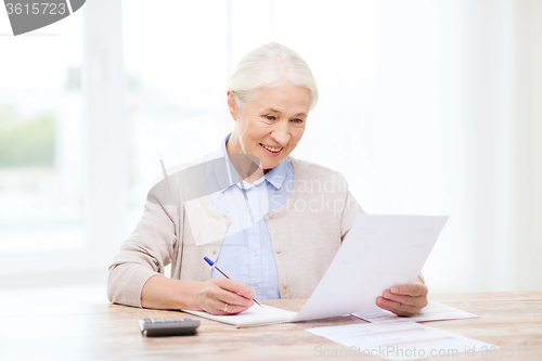 Image of senior woman with papers and calculator at home