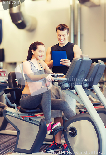 Image of happy woman with trainer on exercise bike in gym