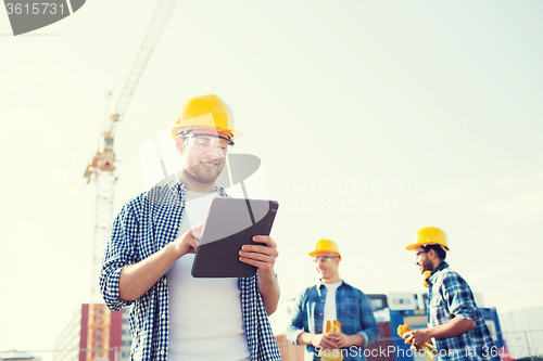 Image of smiling builders in hardhats with tablet pc