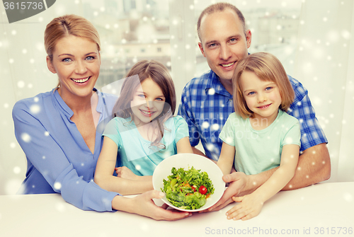 Image of happy family with two kids showing salad in bowl