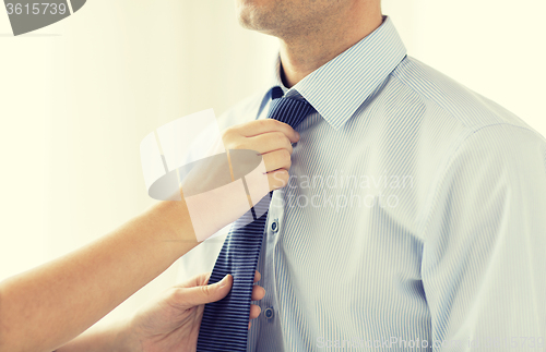 Image of close up of woman hands adjusting tie on mans neck