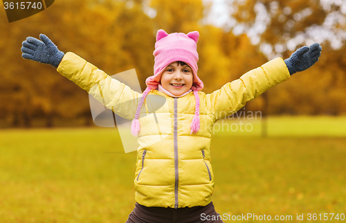 Image of happy little girl with raised hands outdoors