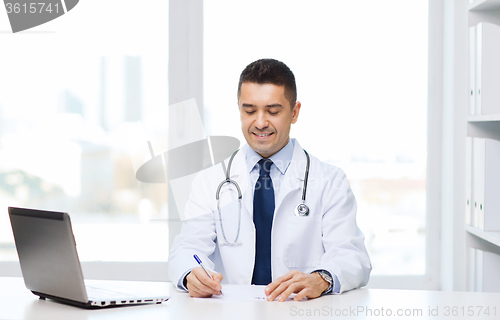 Image of smiling male doctor with laptop in medical office