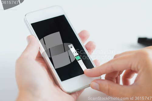 Image of close up of woman with smartphone doing blood test