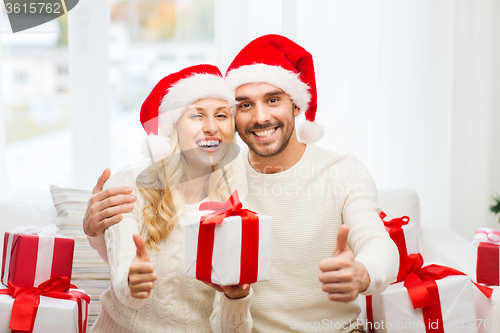 Image of happy couple with christmas gifts and thumbs up