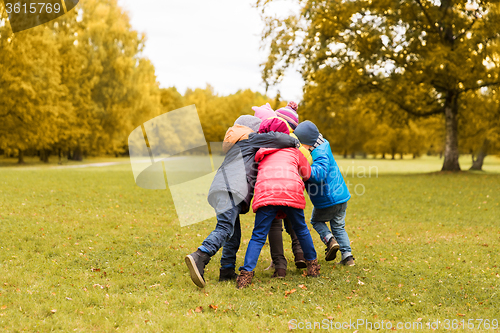 Image of group of happy children hugging in autumn park