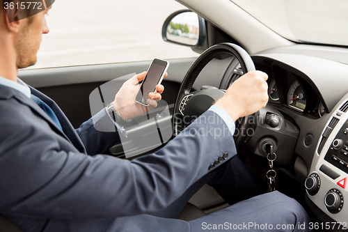 Image of close up of man with smartphone driving car