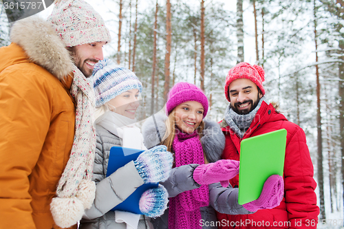 Image of smiling friends with tablet pc in winter forest