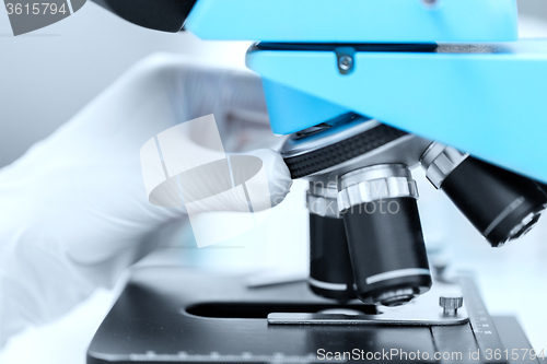 Image of close up of scientist hand setting microscope