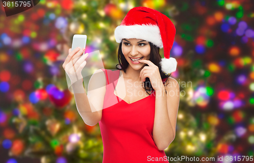 Image of woman in santa hat taking selfie by smartphone